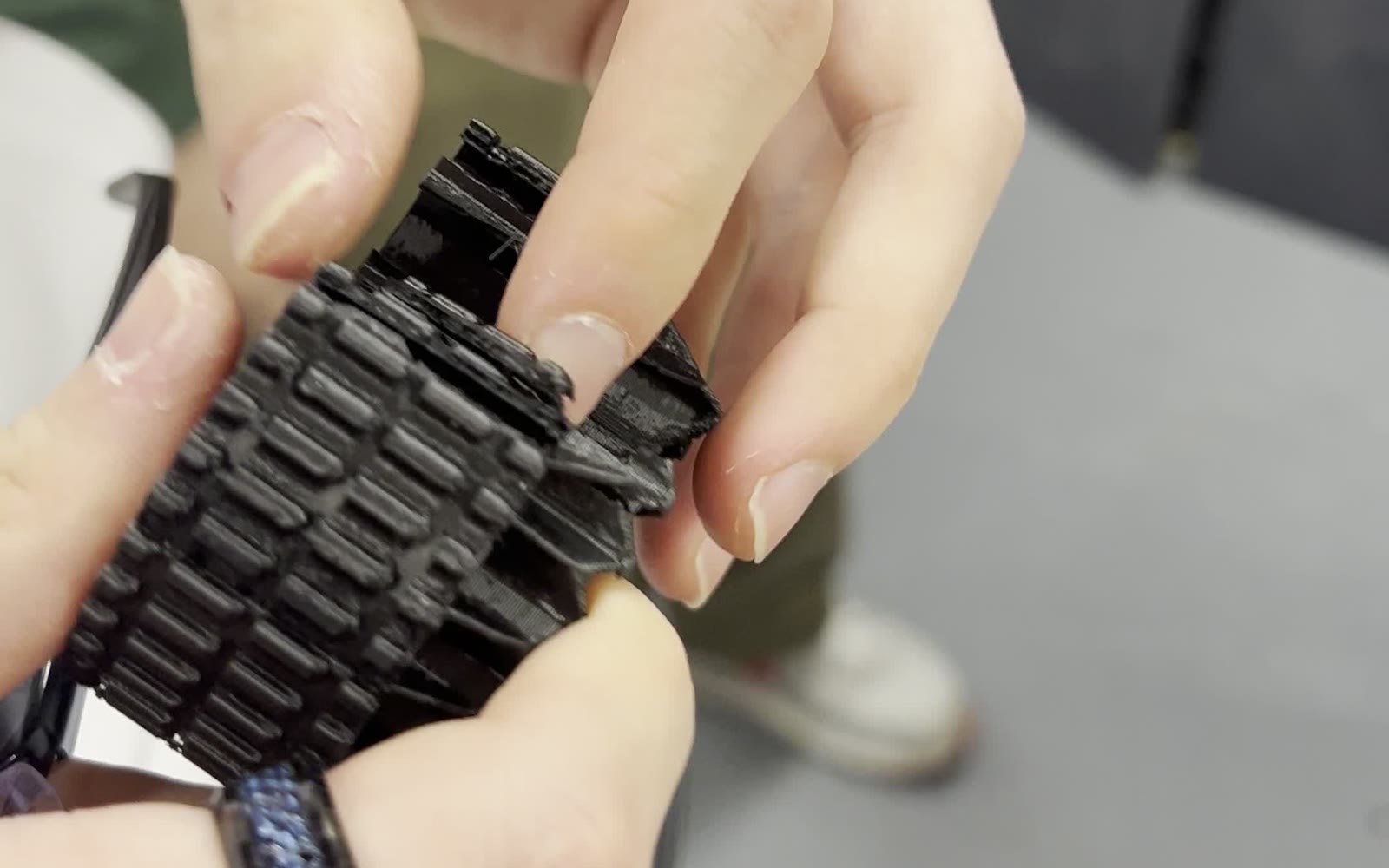 Hands inspecting the tread of a 3D-printed tire after testing