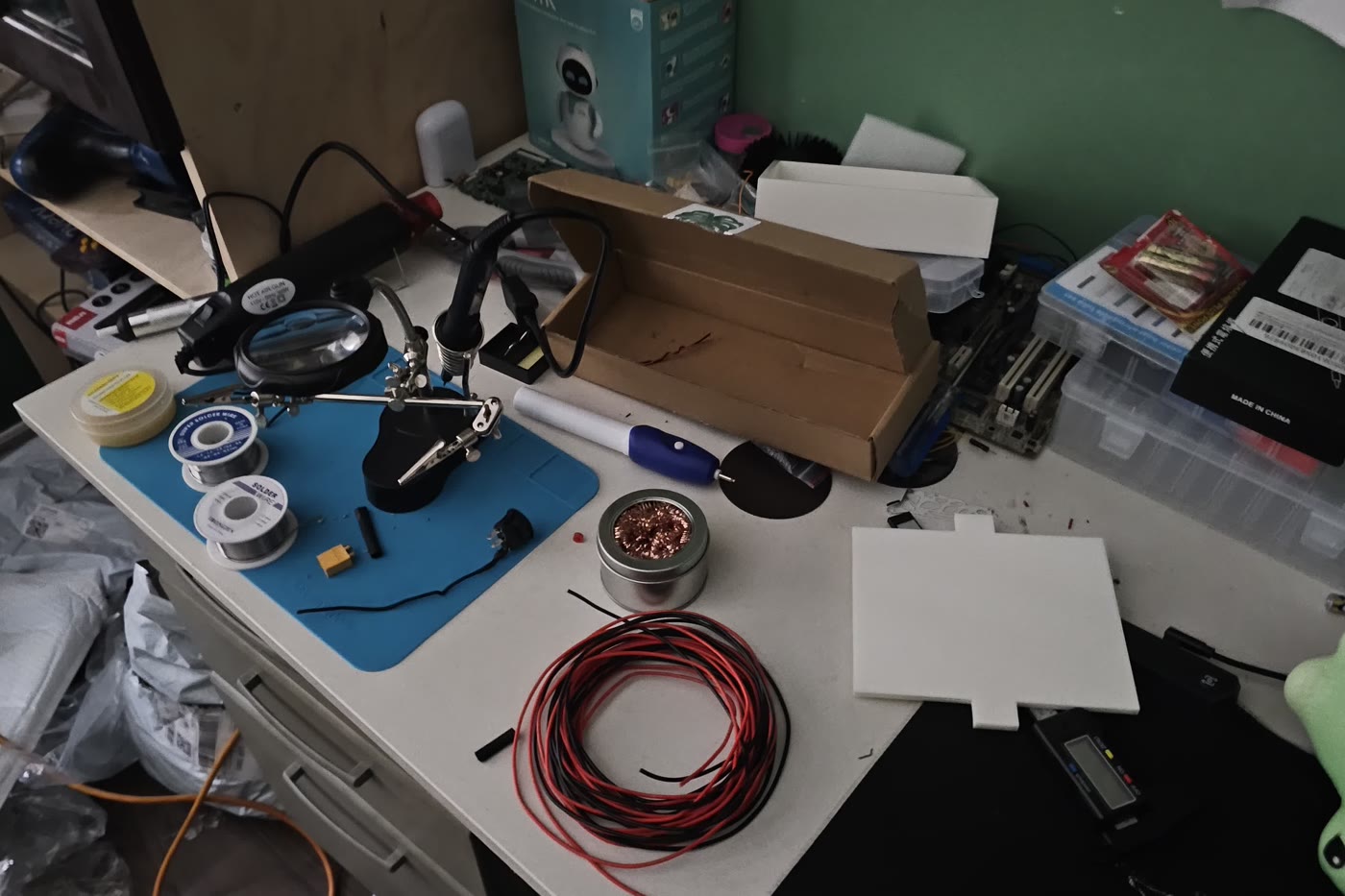 A soldering station with a helping-hands tool, solder spools, and wire coils