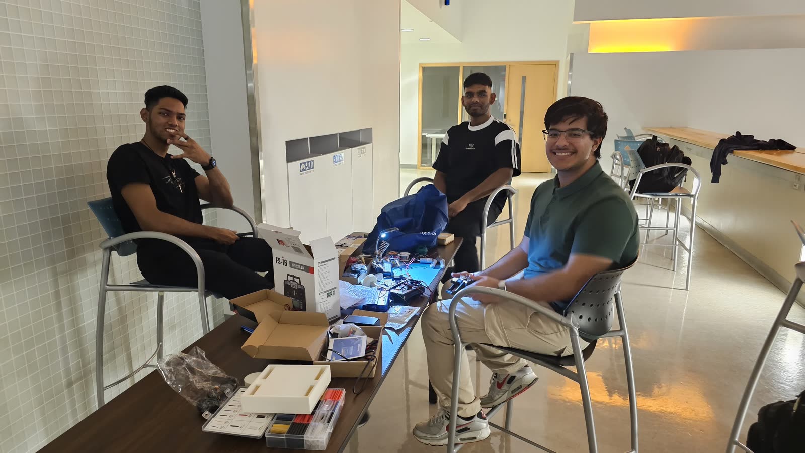 The three founders unboxing an RC transmitter and wiring kits before their first competition