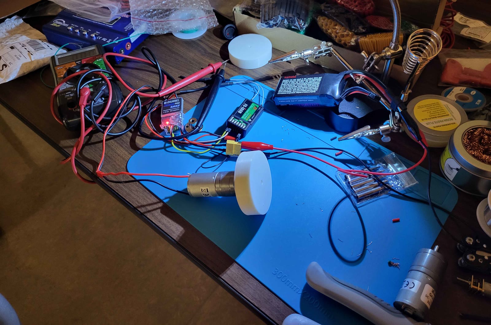 An electronics workbench with a multimeter, ESC, receiver, and LiPo battery